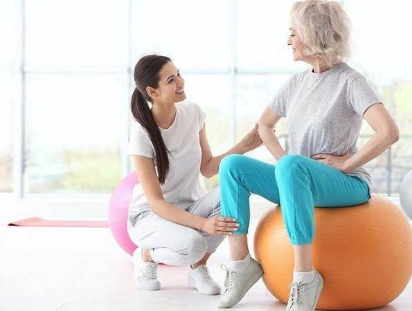 Dona adulta fent exercicis amb ajuda d'una fisioterapeuta