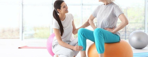 Dona adulta fent exercicis amb ajuda d'una fisioterapeuta