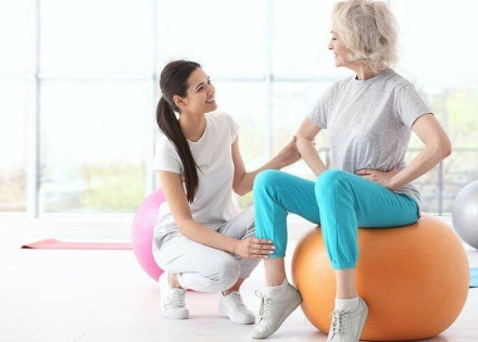 Dona adulta fent exercicis amb ajuda d'una fisioterapeuta