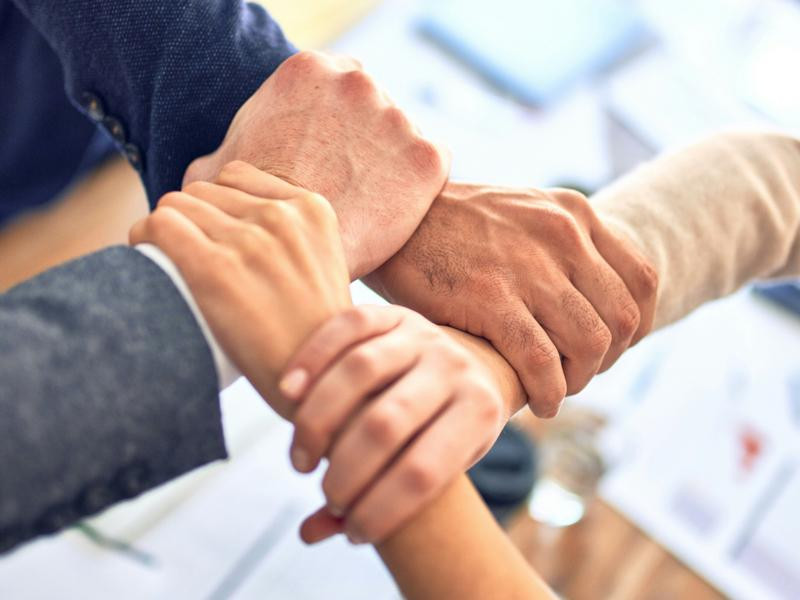 Cuatro manos entrelazadas formando equipo