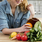 mujer cabello rubio con frutas y verduras encima de la mesa de la cocina